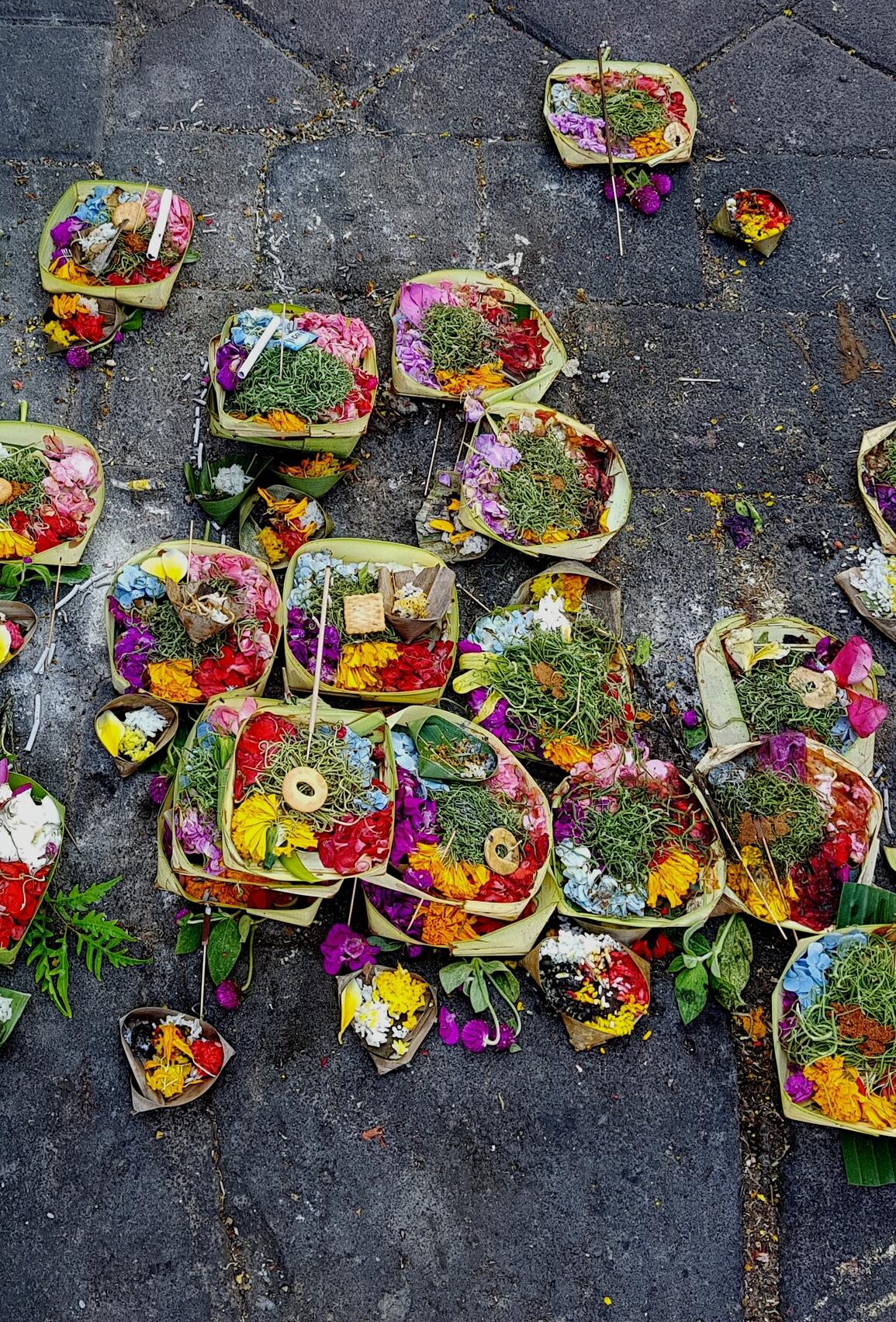 Small square containers made of palm leaves full flower offerings and an incense stick